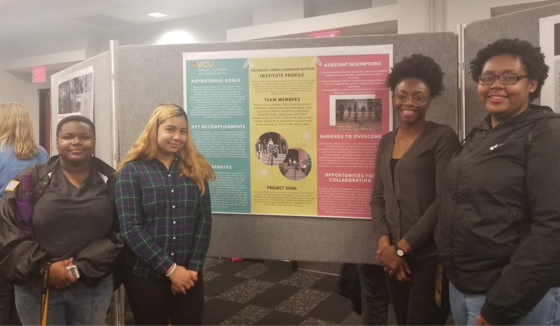 Four students pose in front of their poster
